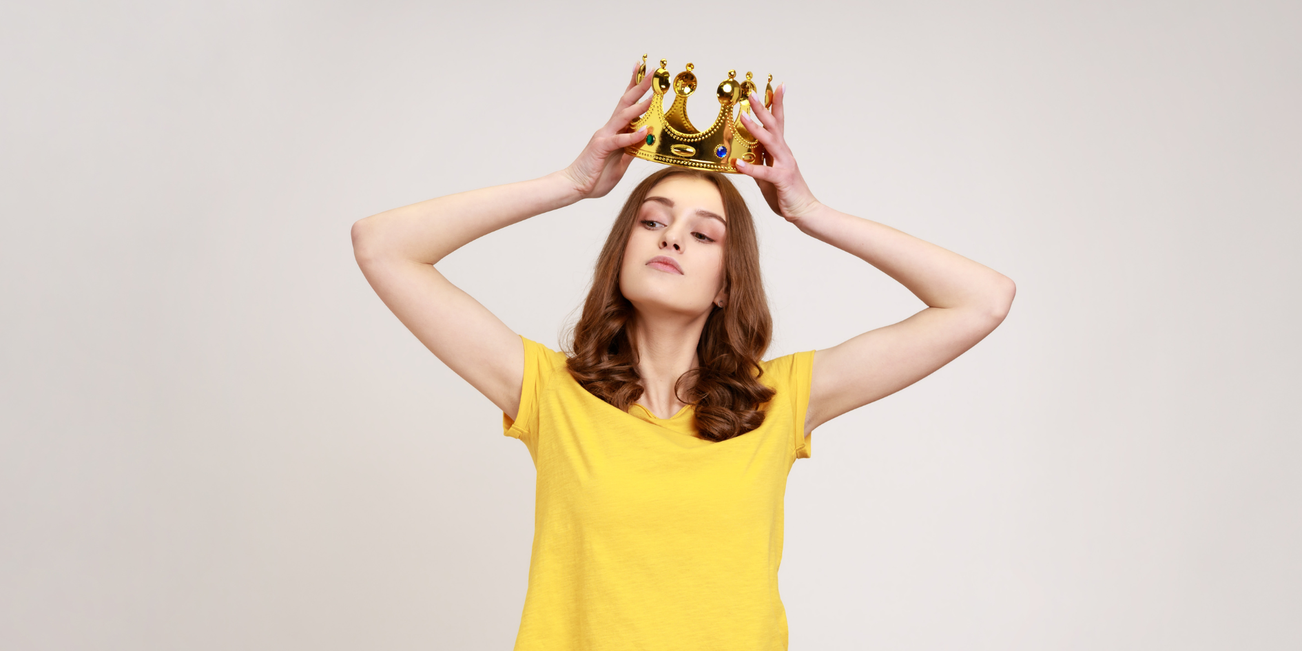 woman in a yellow tshirt putting a crown on her head